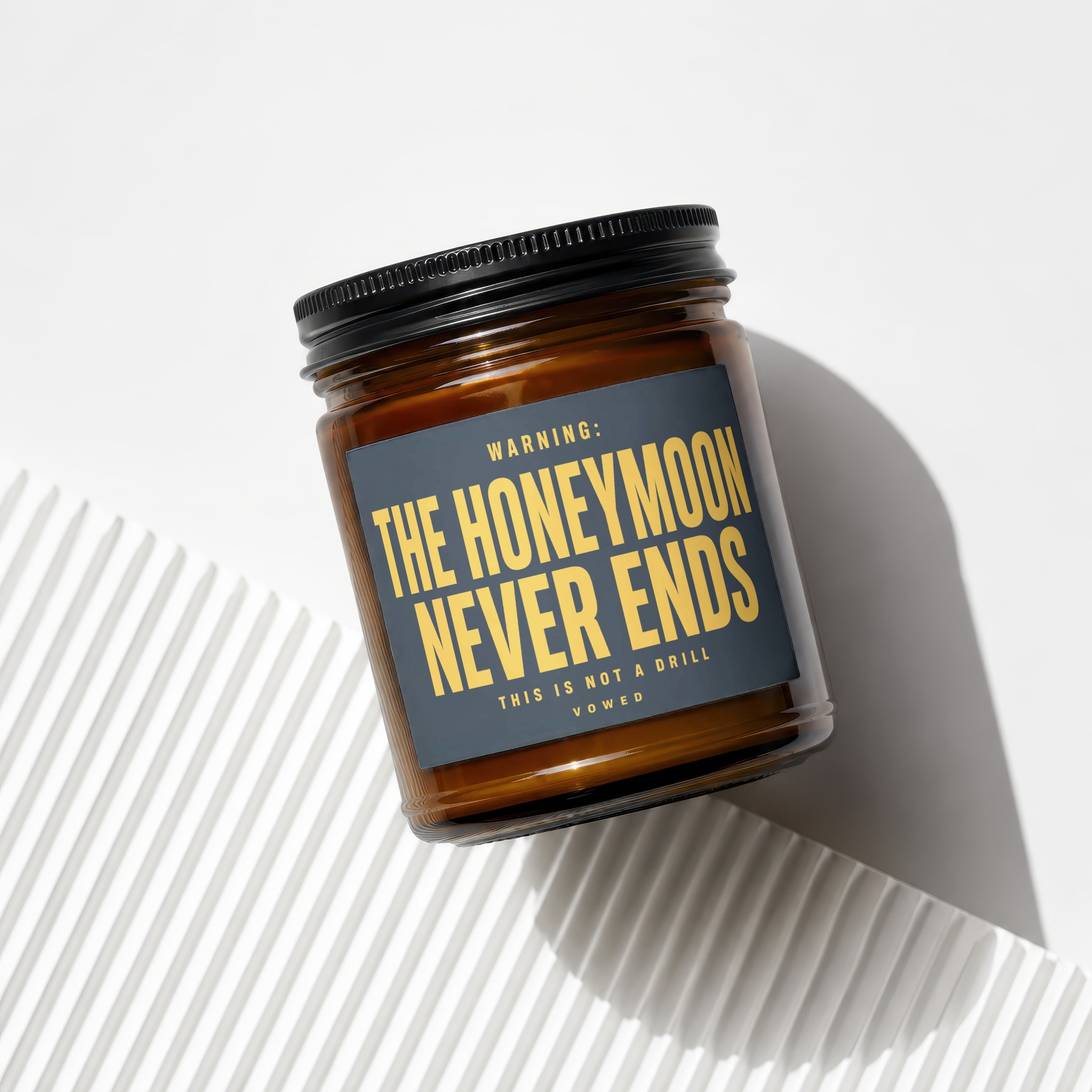Amber jar candle with black lid, labeled "WARNING: THE HONEYMOON NEVER ENDS."