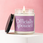 Candle with "Officially spouses" and "vowed" text on purple label, lid off.