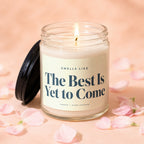 Scented candle with label "The Best Is Yet to Come", surrounded by pink flower petals.