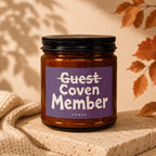Brown glass candle with purple label reading "Guest Coven Member Vowed".