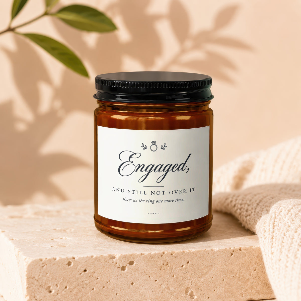 Amber jar candle with a label that reads "Engaged, and still not over it".