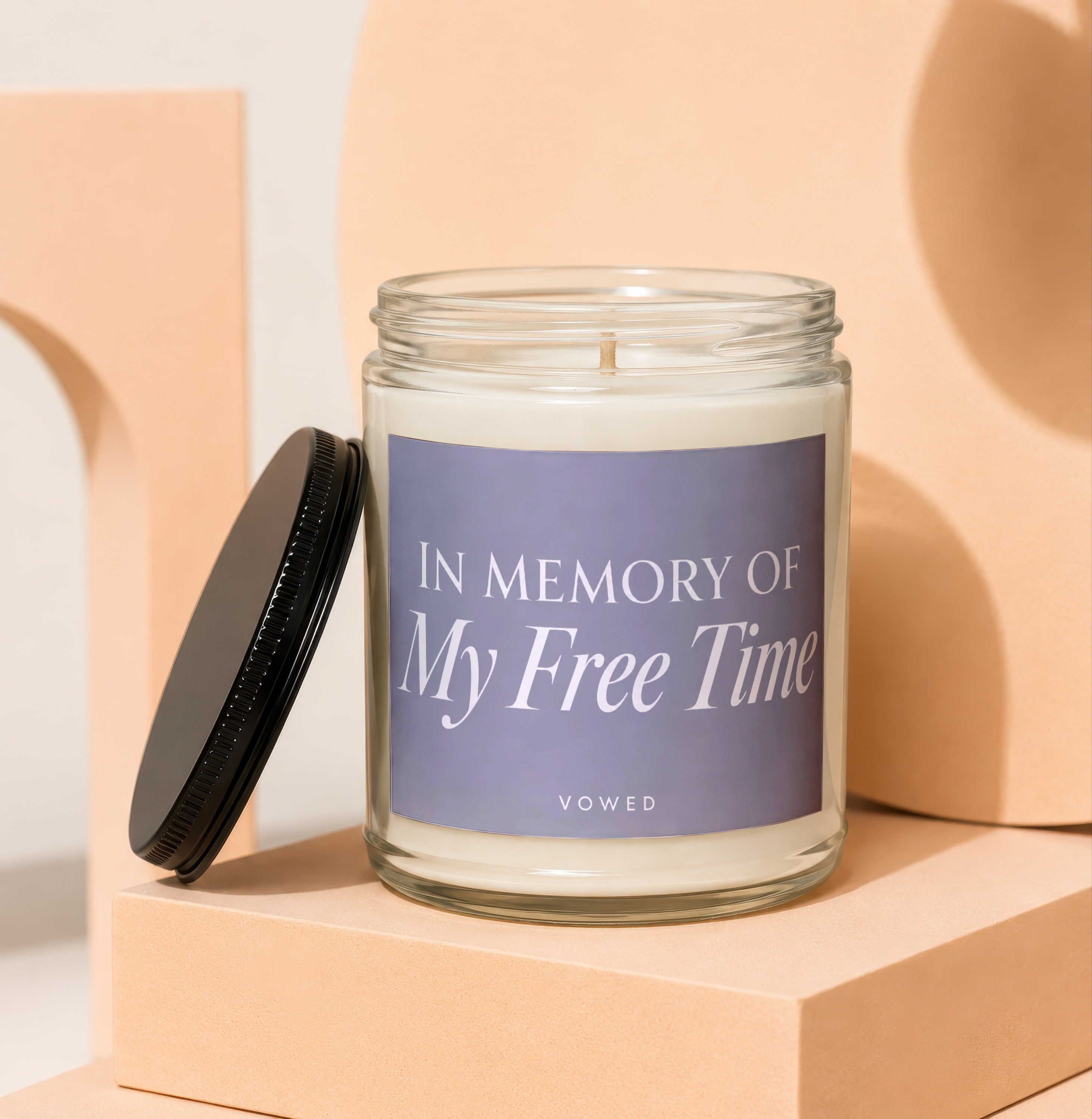 Candle with "In Memory Of My Free Time" text and "vowed" on a light purple label.