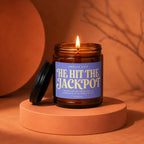 Amber candle with lavender label reading "Smells like He Hit the Jackpot".
