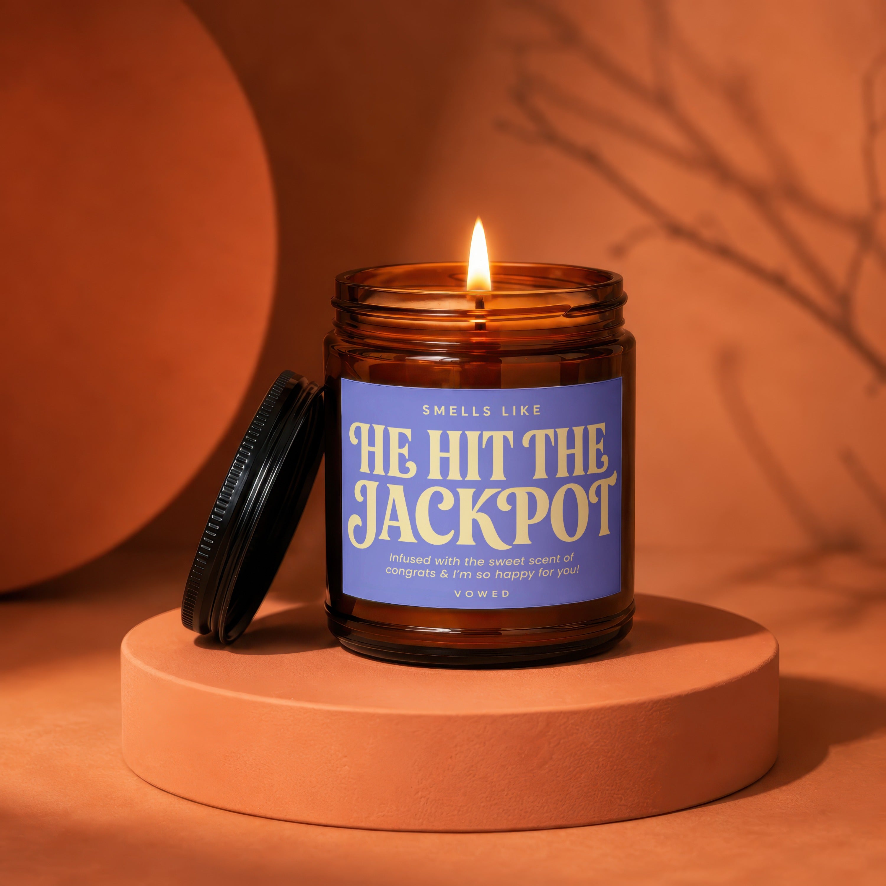 Amber candle with lavender label reading "Smells like He Hit the Jackpot".