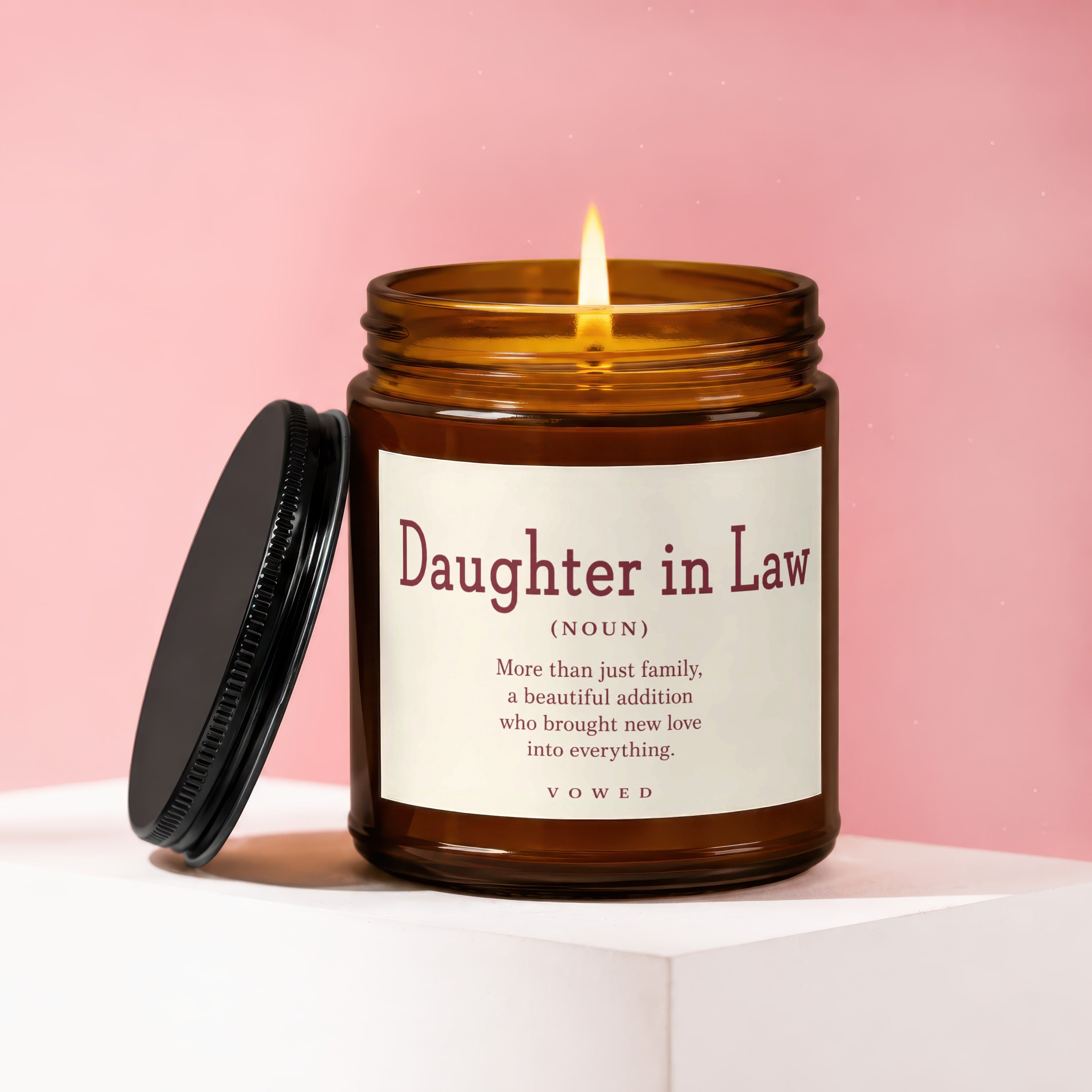Amber candle with "Daughter in Law" poem, lit flame, pink background.