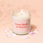 Lit candle in a jar with pink label that reads "From Maybe to Forever. VOWED."