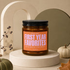 Amber jar candle with "First Year Favorites" orange label and black lid.