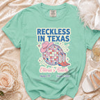 Teal t-shirt with "Reckless in Texas" and party graphics for Olivia's Bach in Austin.