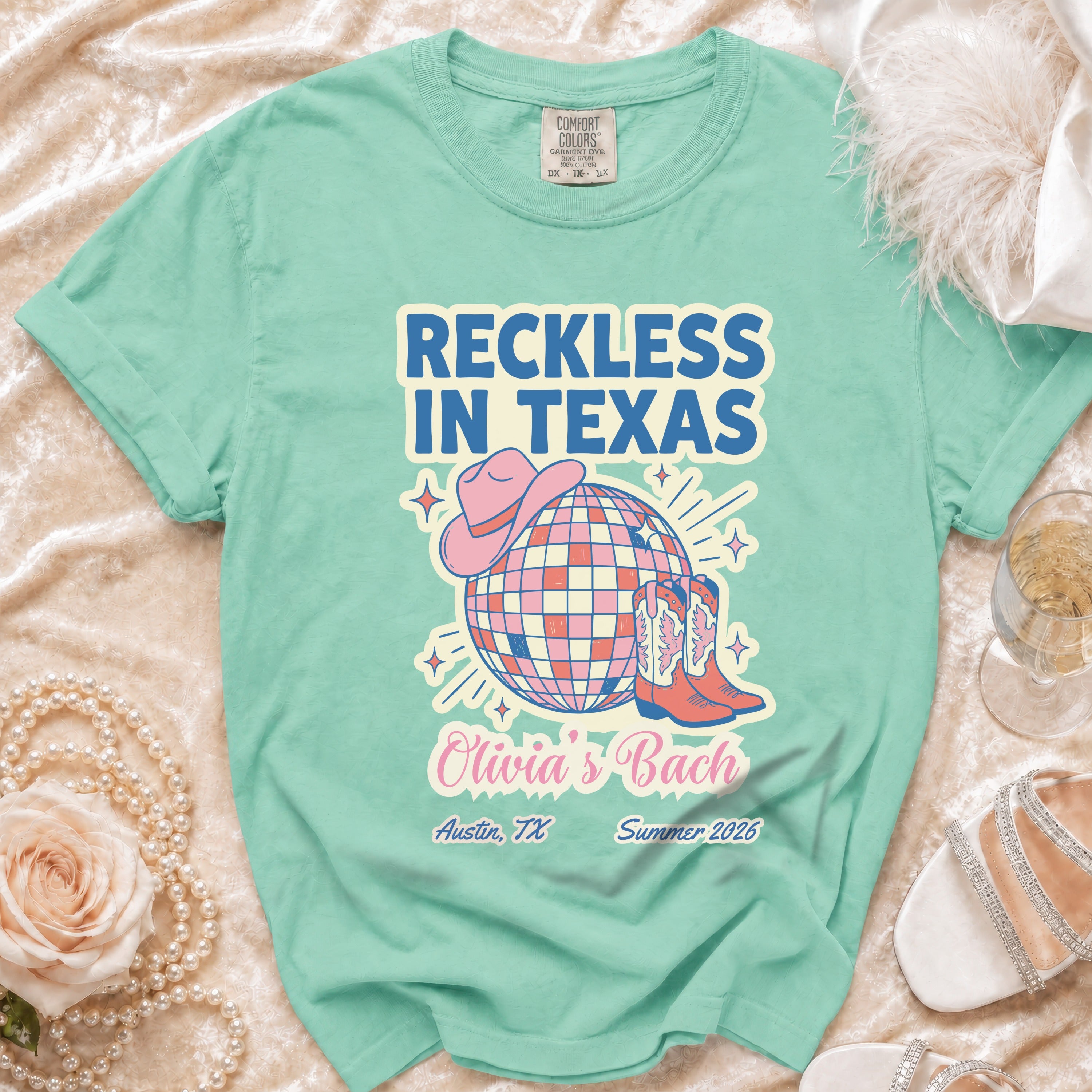Teal t-shirt with "Reckless in Texas" and party graphics for Olivia's Bach in Austin.