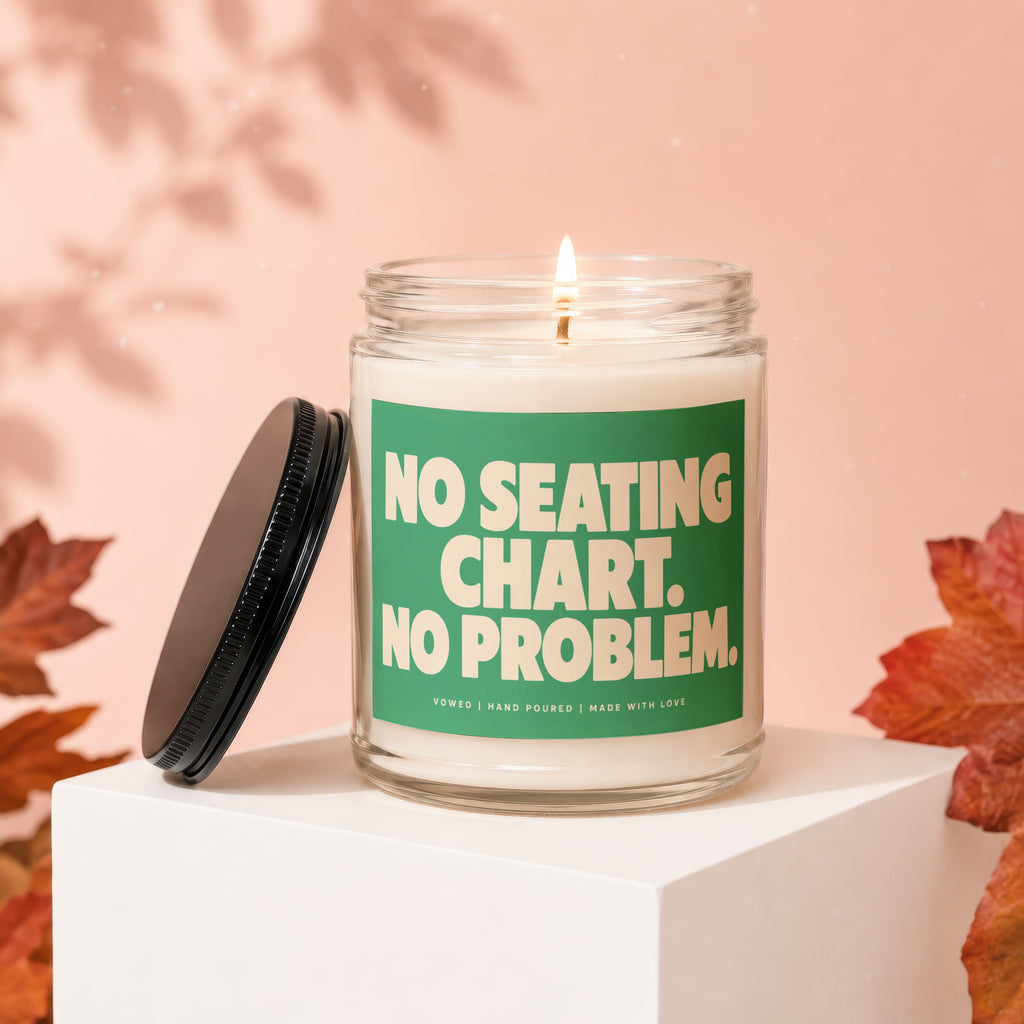 Candle with lit wick and green label reading "No Seating Chart. No Problem."
