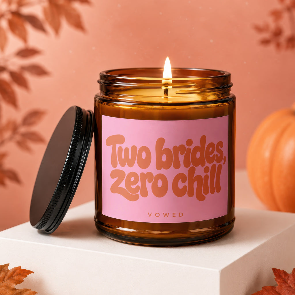 Amber jar candle with pink label reading "Two brides, zero chill" and "VOWED".