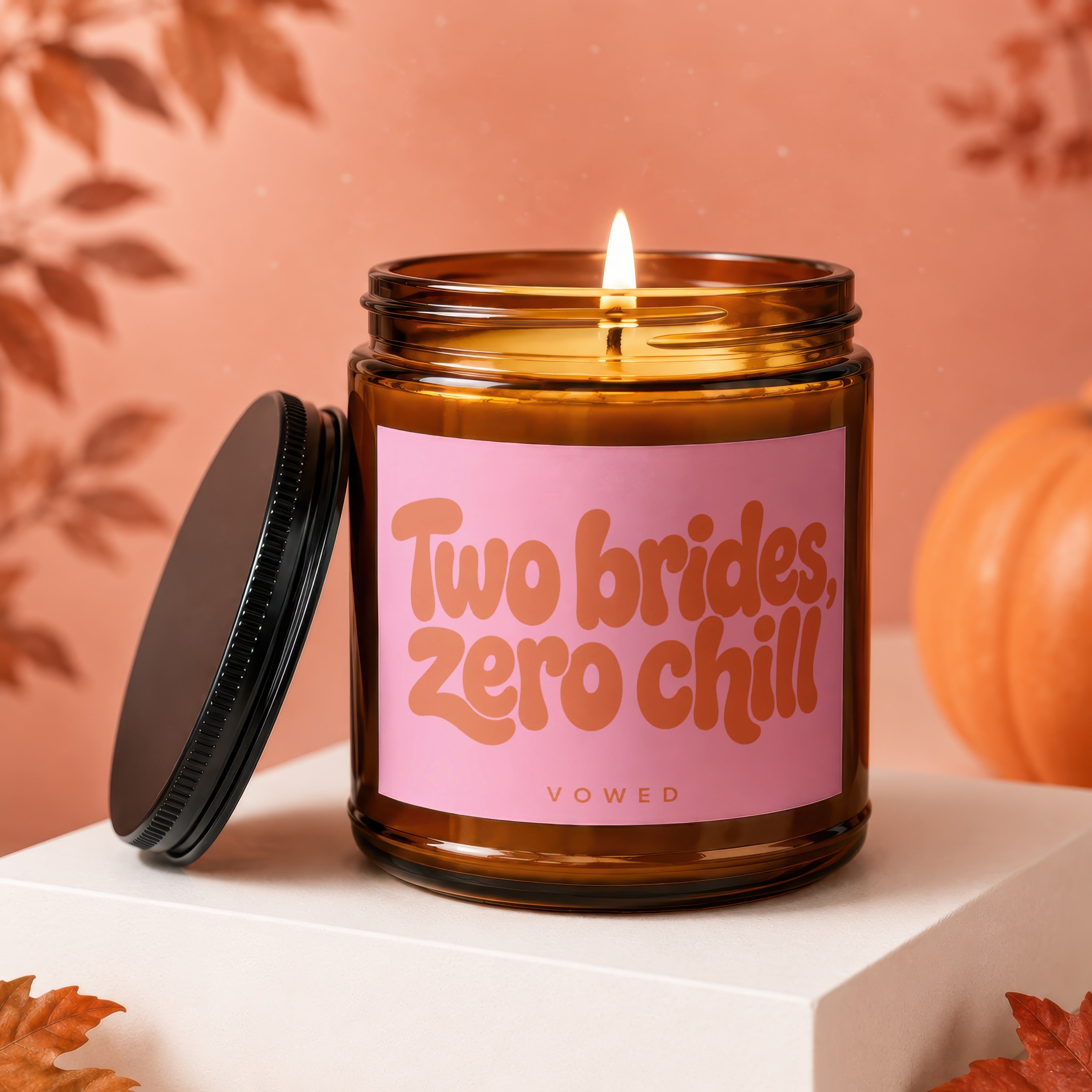 Amber jar candle with pink label reading "Two brides, zero chill" and "VOWED".