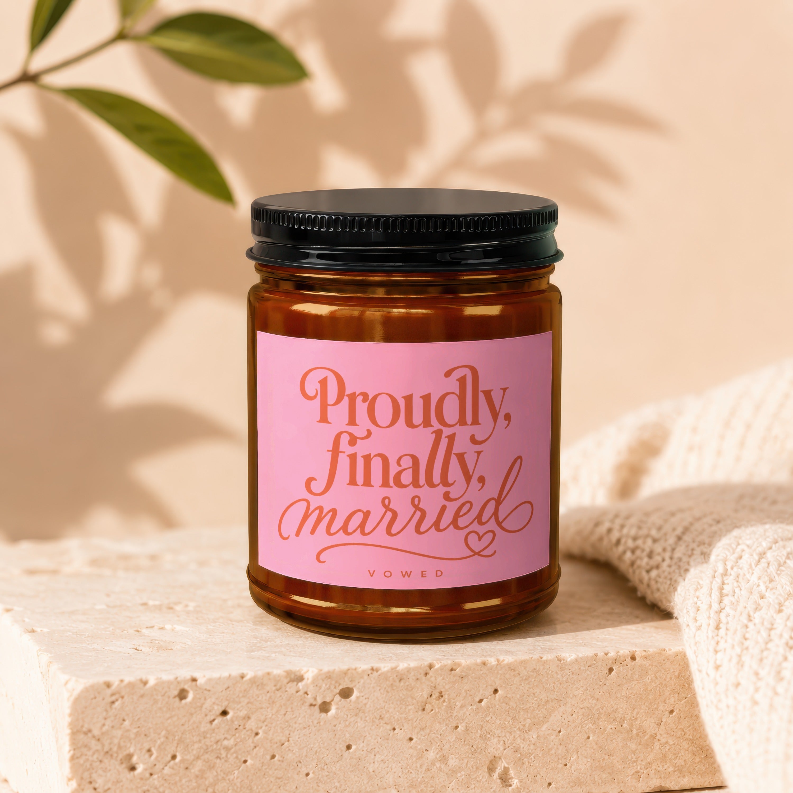 Brown candle jar with pink label reading "Proudly, finally, married" in cursive orange font.