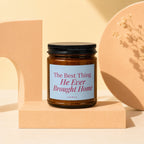 Amber jar candle with black lid, label reads "The Best Thing He Ever Brought Home".