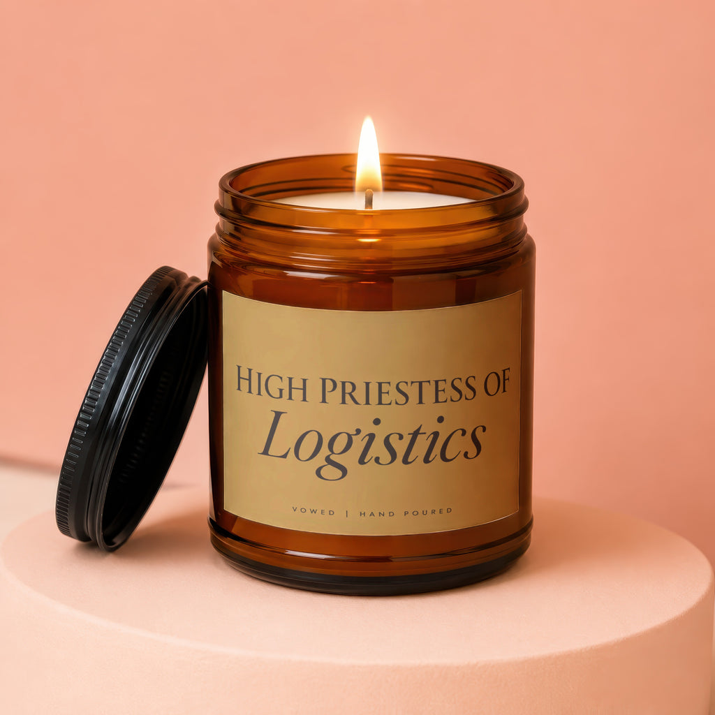 Amber jar candle with lit wick and black lid, reading "High Priestess of Logistics".