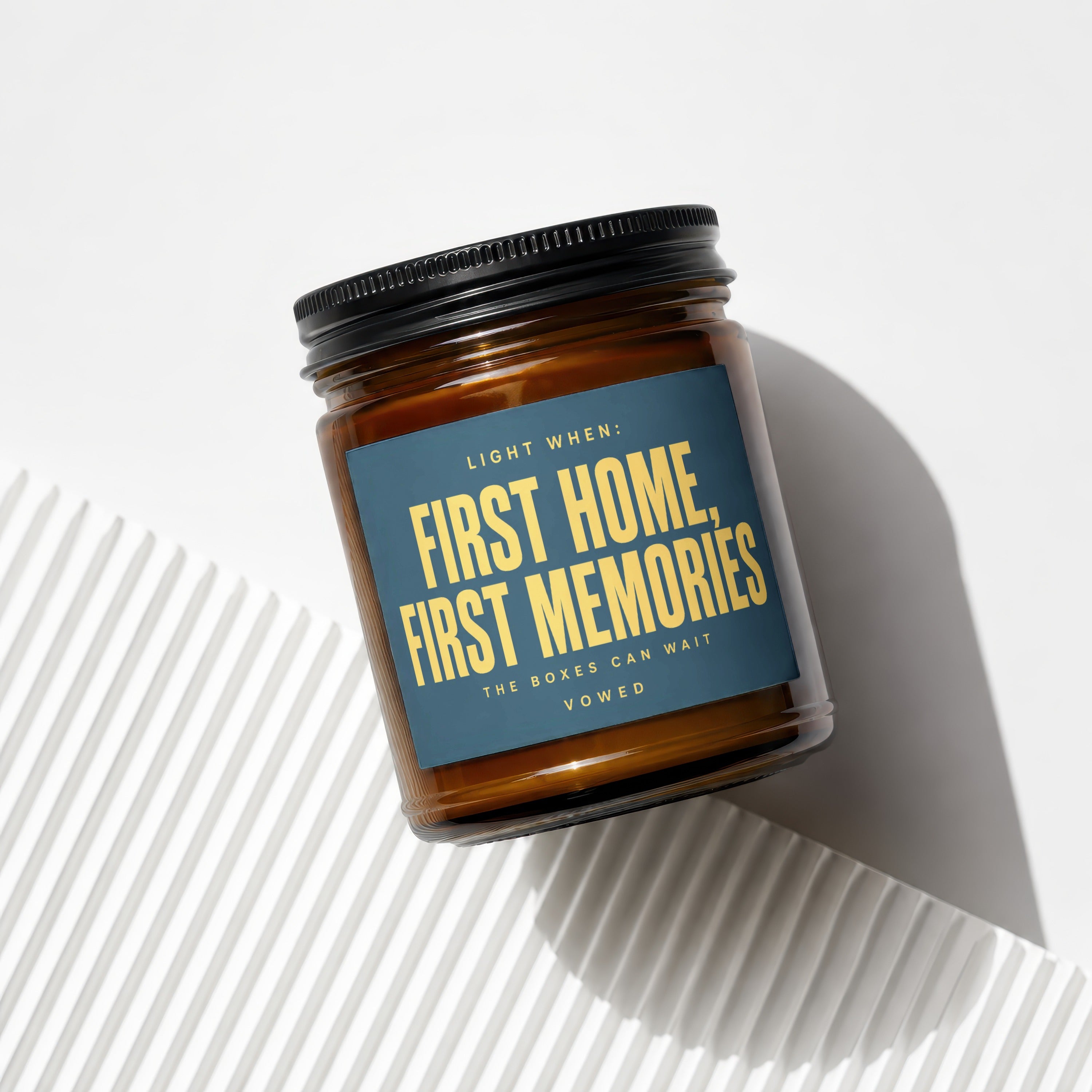 Amber glass candle with dark blue label that reads "First Home, First Memories."