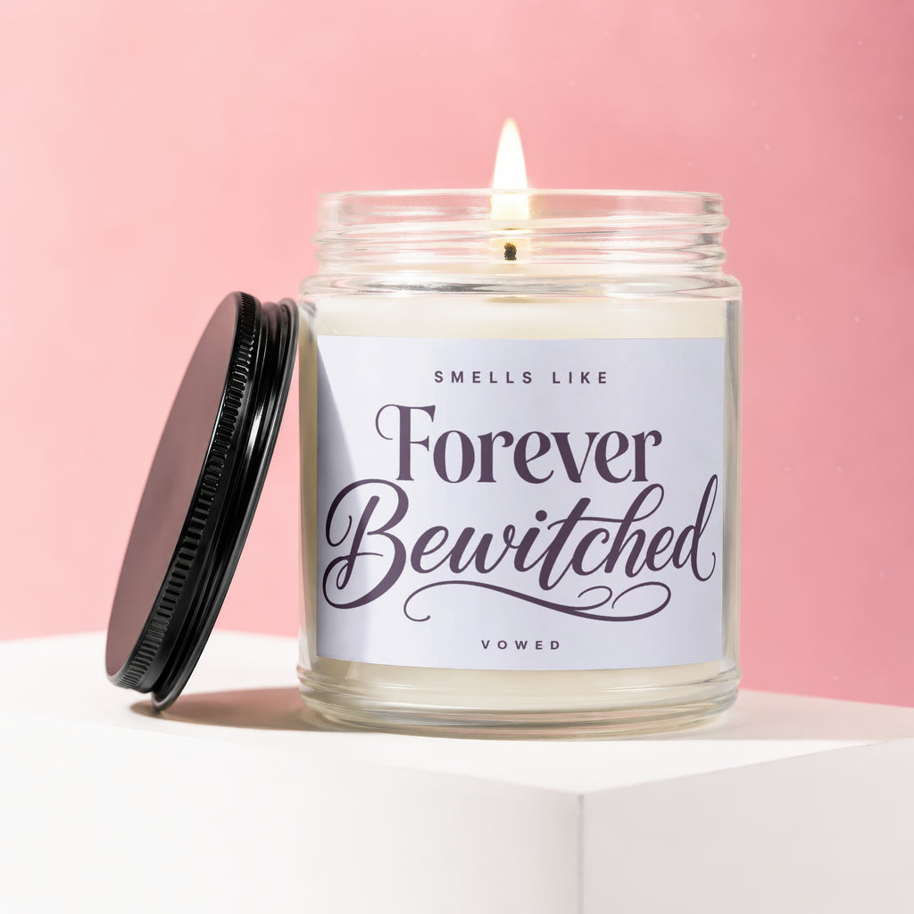 Jar candle lit with flame, lid off, labeled "Smells Like Forever Bewitched Vowed".