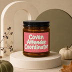 Amber candle with pink label reading "Coven Attendee Coordinator," VOWED.
