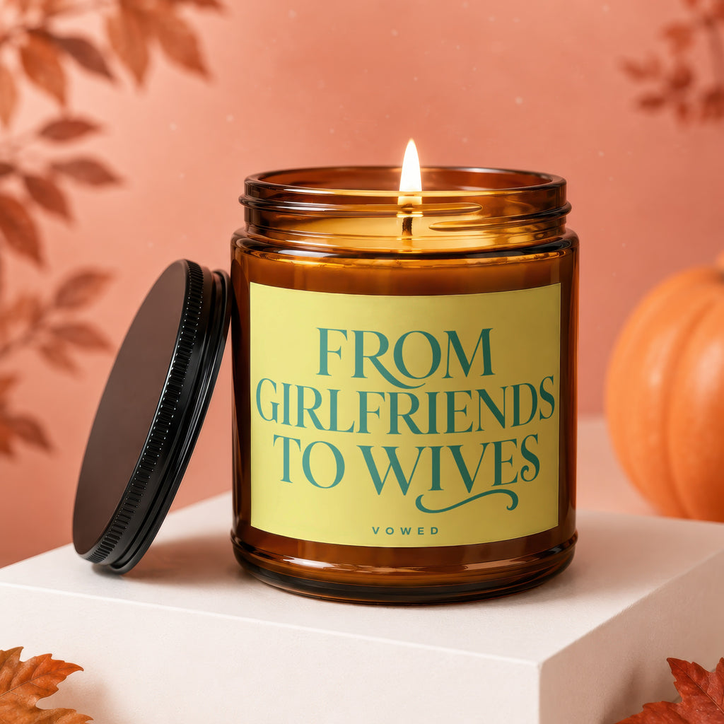 Amber candle with lit flame and yellow label reading "FROM GIRLFRIENDS TO WIVES".