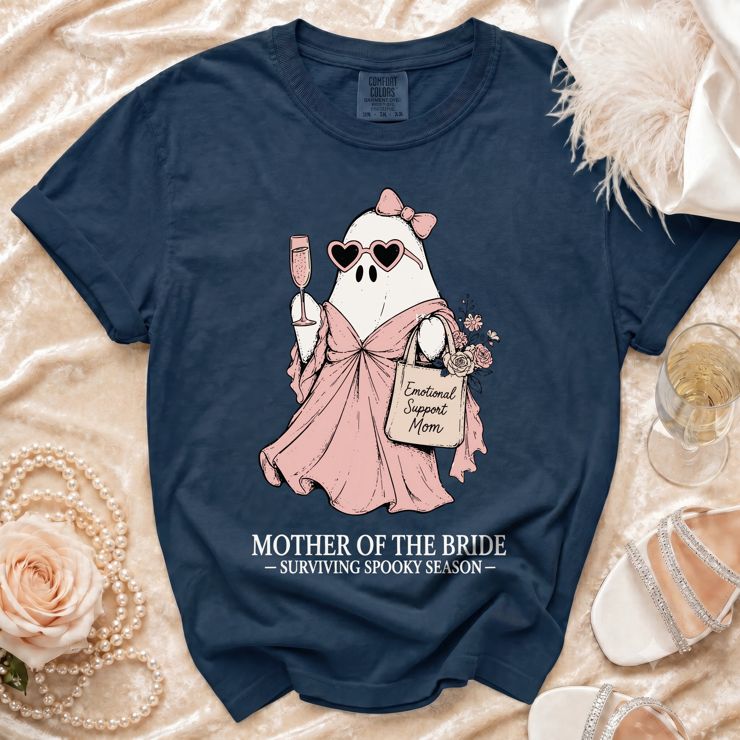 Navy t-shirt with ghost graphic holding champagne, heart sunglasses, and "Emotional Support Mom" tote bag.