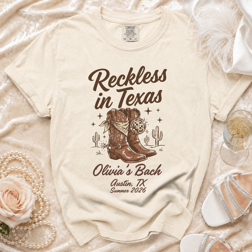 Cream t-shirt with "Reckless in Texas" and cowboy boots graphic, "Olivia's Bach Austin, TX Summer 2026".