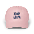 A light pink baseball cap features embroidered blue text reading BOOTS AND BLING centered on the front.