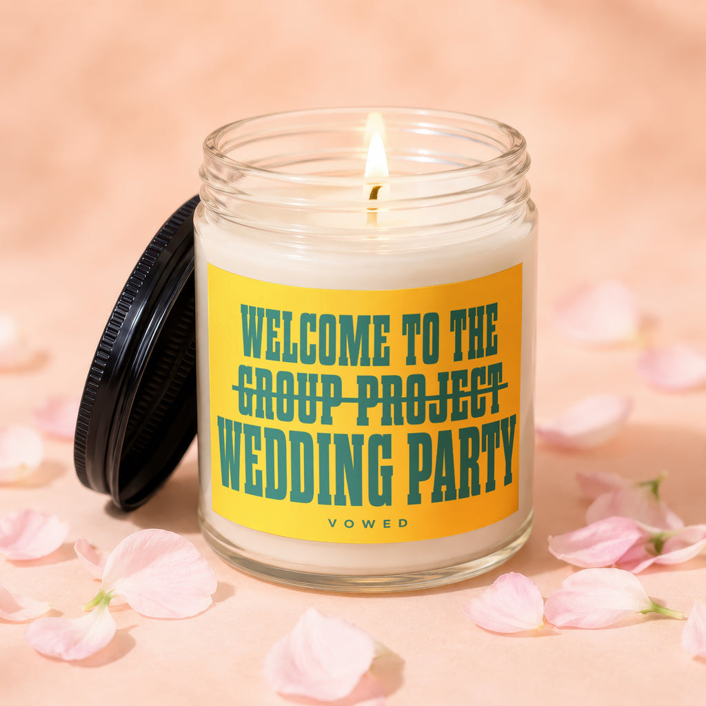 Jar candle with lit wick and yellow label reading "Welcome to the Group Project Wedding Party".