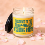 Jar candle with lit wick and yellow label reading "Welcome to the Group Project Wedding Party".