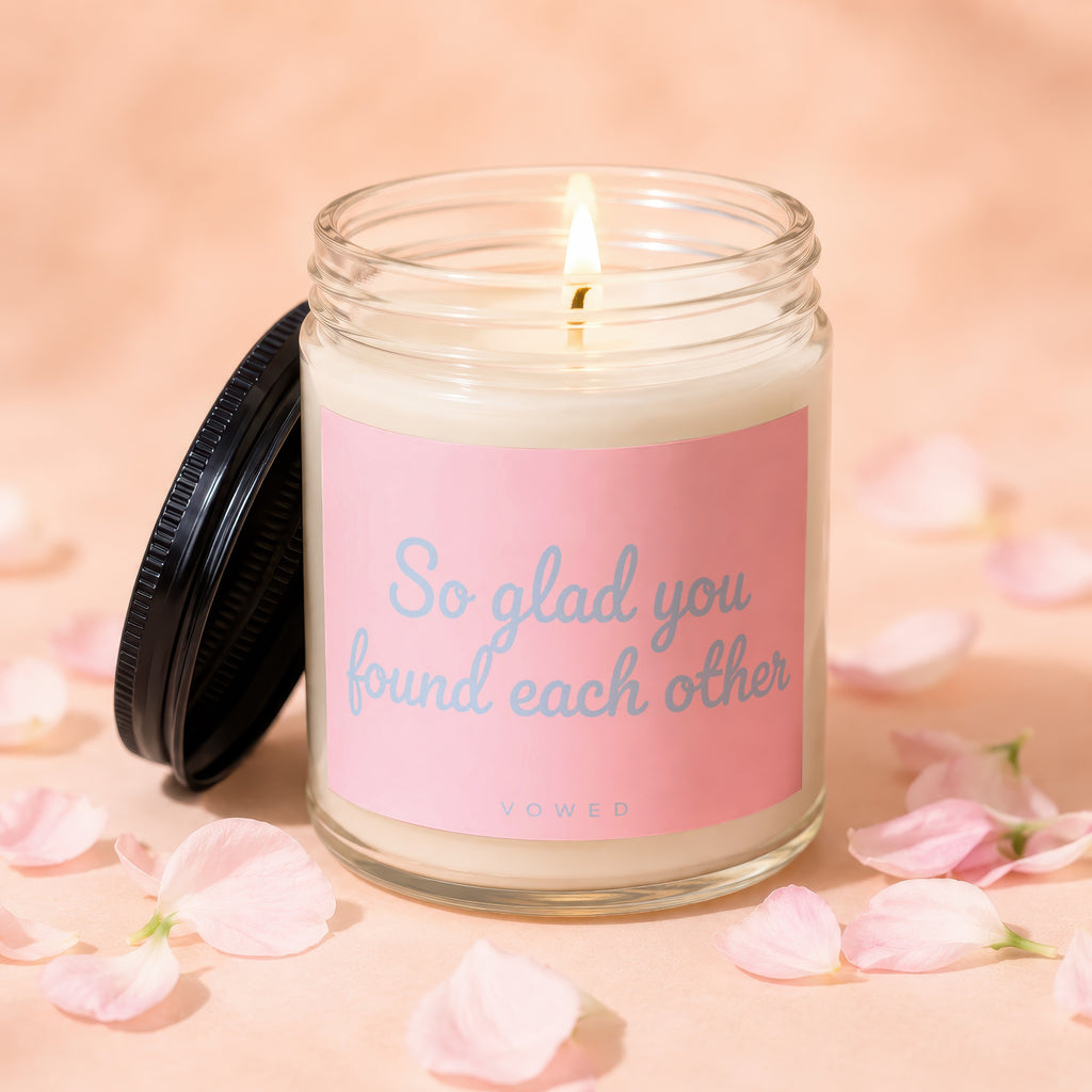 Candle with lit flame and pink label reading "So glad you found each other".