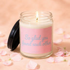 Candle with lit flame and pink label reading "So glad you found each other".