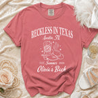 Coral t-shirt with "Reckless in Texas Austin, TX" and cowboy boot graphic.