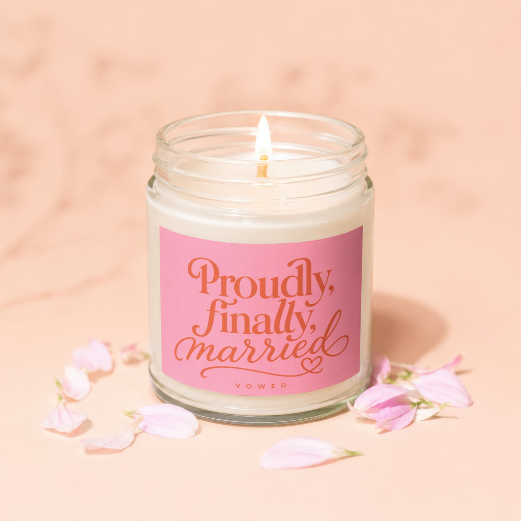 Candle with "Proudly, finally, married" text on pink label, surrounded by petals.