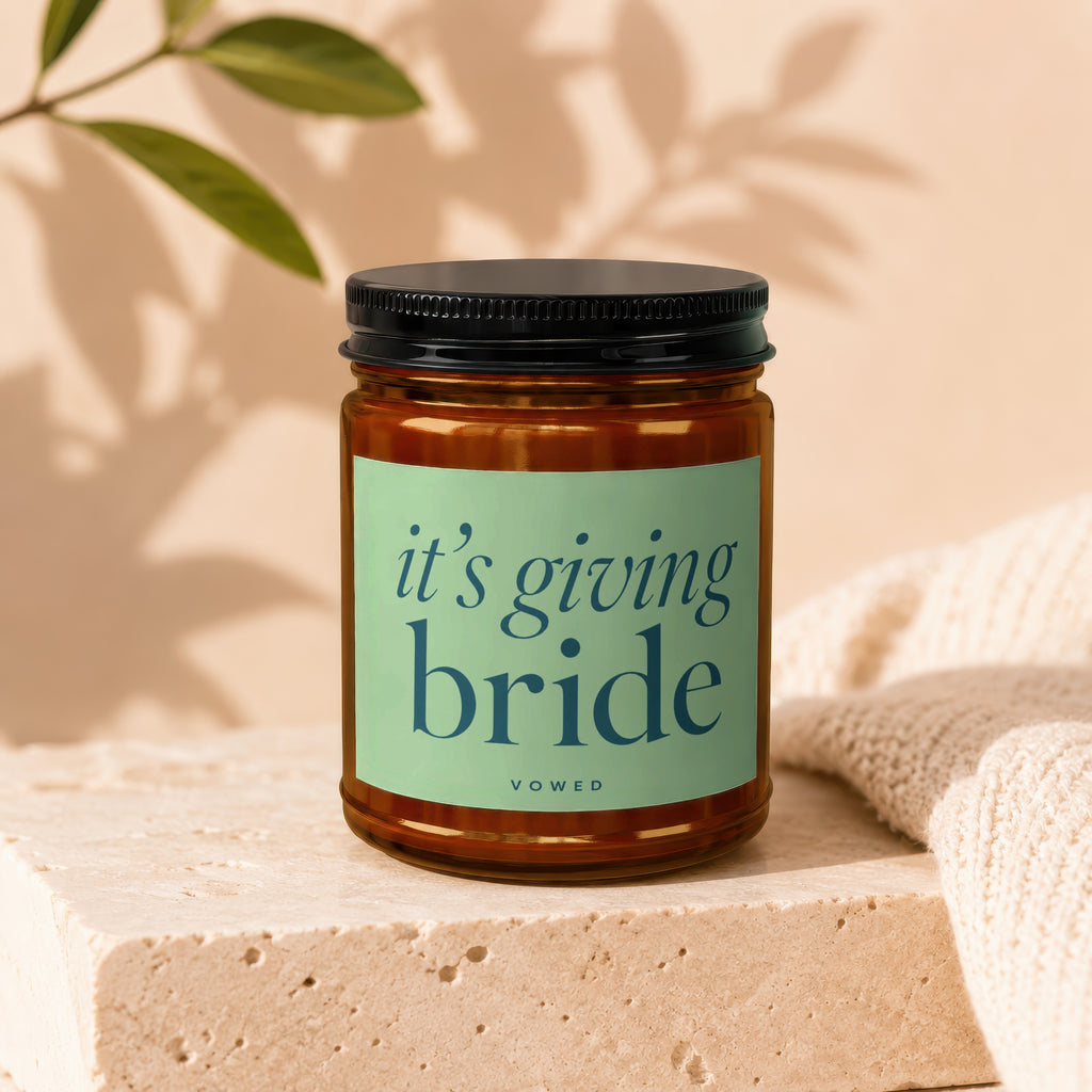 Amber jar candle with green label reading "it's giving bride" VOWED.