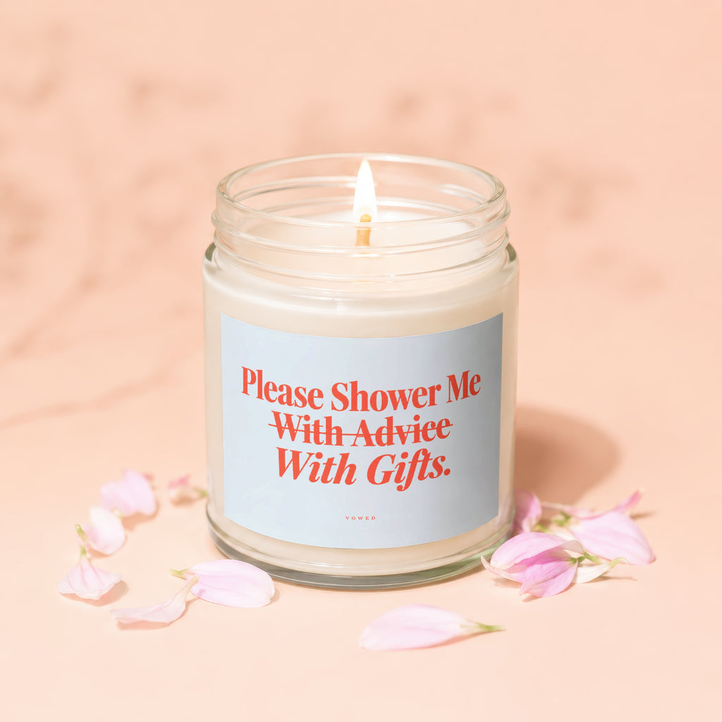 Lit candle in a jar with a label reading "Please Shower Me With Advice With Gifts."