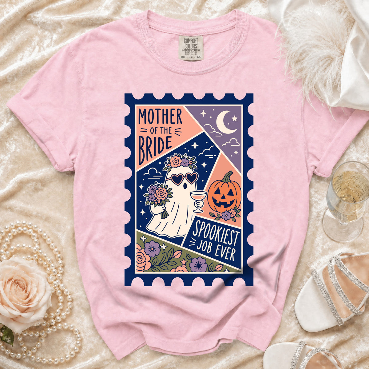 Pink t-shirt with graphic of a ghost bride holding flowers and a drink, text reads "Mother of the Bride Spookiest Job Ever".