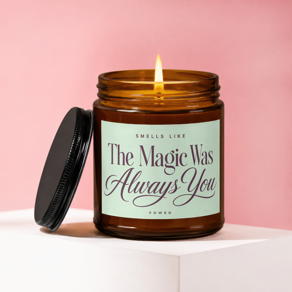 Amber glass candle burning, lid off, with "Smells Like The Magic Was Always You" text.