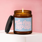 Lit amber glass candle with black lid and "Two rings, zero chill" text.
