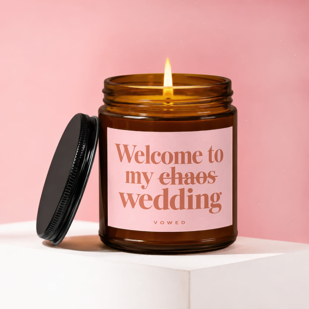 Amber jar candle with lit wick and black lid, reads "Welcome to my chaos wedding".