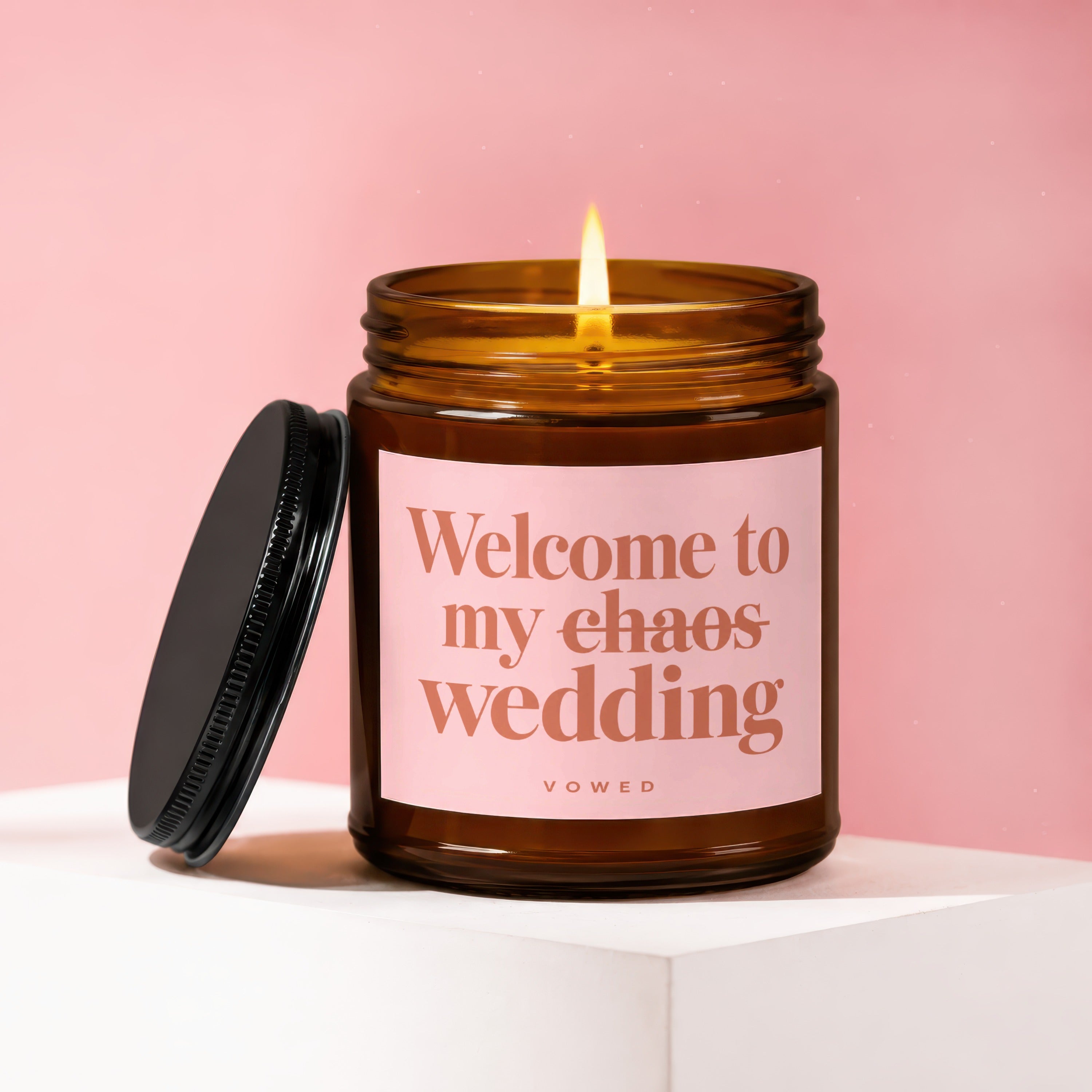 Amber jar candle with lit wick and black lid, reads "Welcome to my chaos wedding".