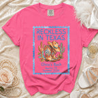 Pink t-shirt with "Reckless in Texas" design, cowboy boots, and cactus.
