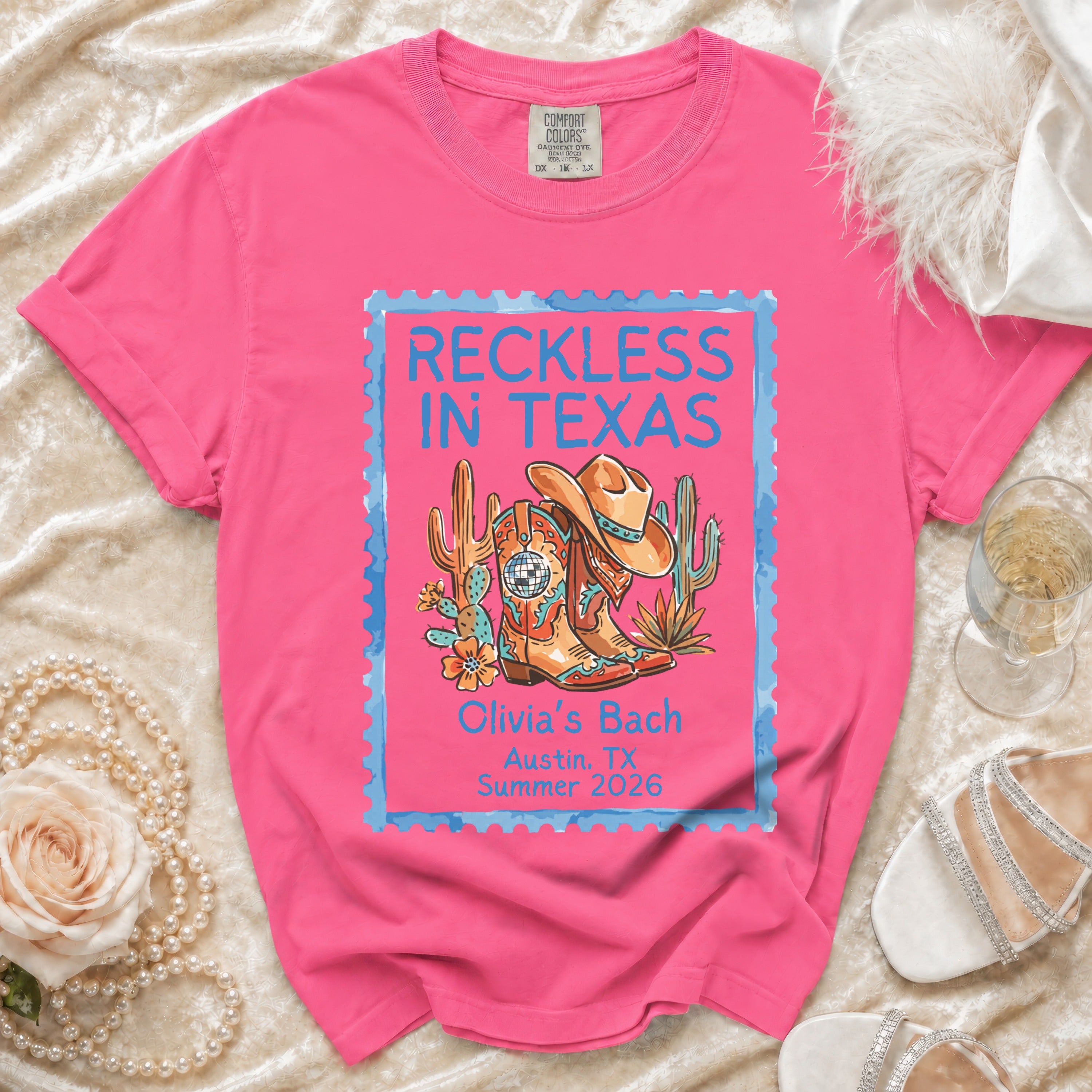 Pink t-shirt with "Reckless in Texas" design, cowboy boots, and cactus.