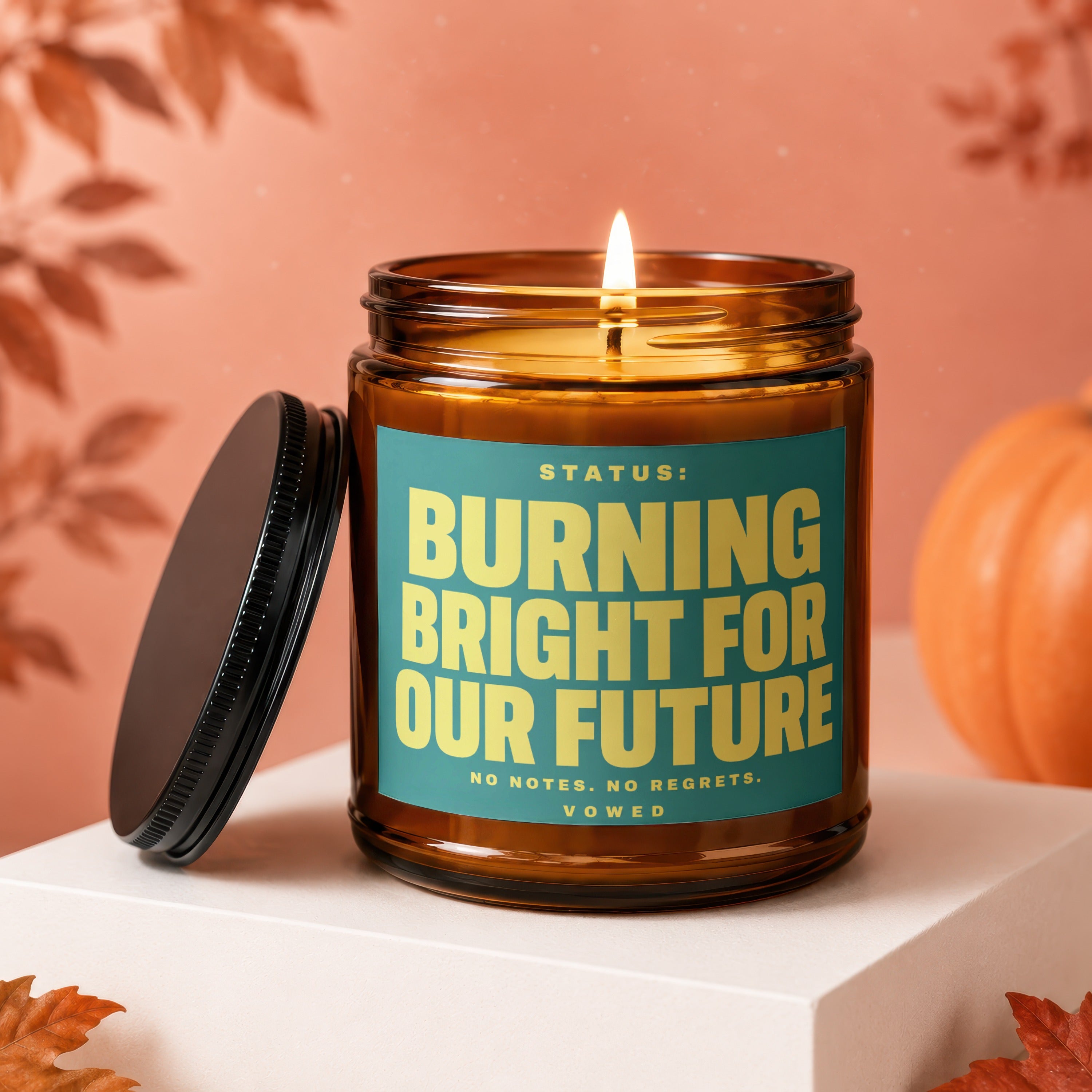 Amber candle with teal label reading "STATUS: BURNING BRIGHT FOR OUR FUTURE".