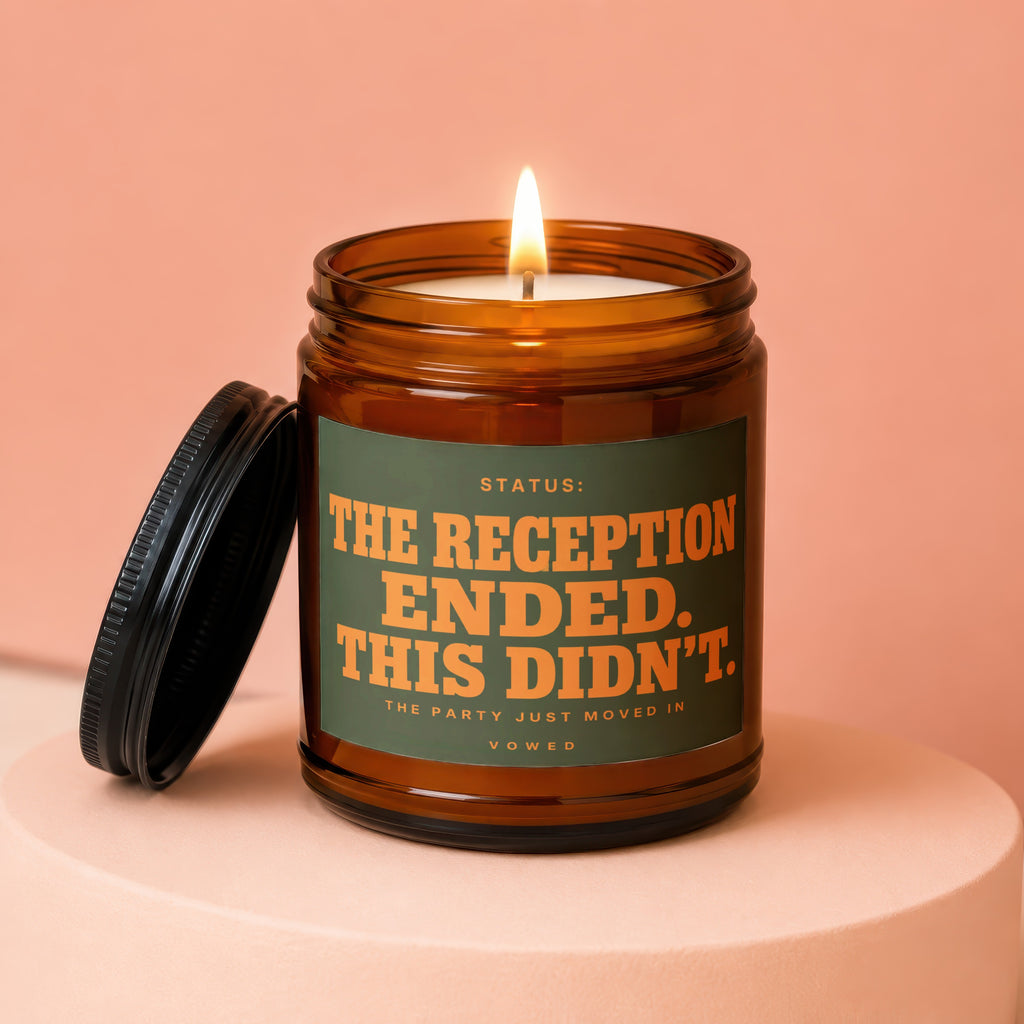 Amber candle with lit wick, reads "STATUS: THE RECEPTION ENDED. THIS DIDN'T. THE PARTY JUST MOVED IN VOWED"