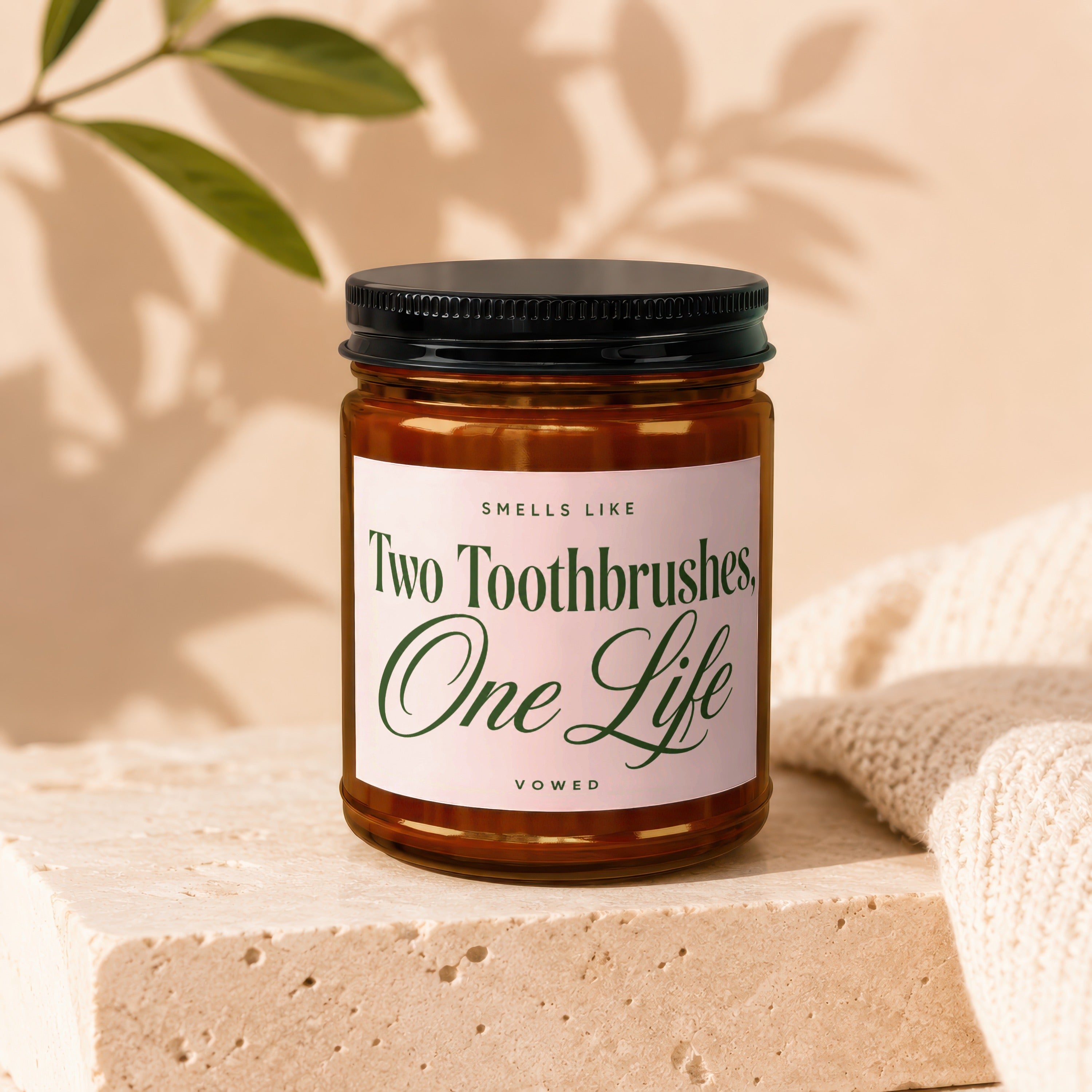 Amber candle with label reading "Smells Like Two Toothbrushes, One Life"