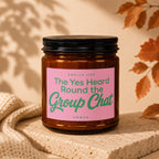 Brown glass candle with pink label reading "The Yes Heard Round the Group Chat"