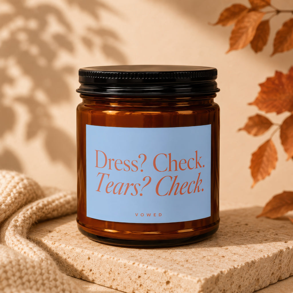 Amber glass candle with light blue label reading "Dress? Check. Tears? Check."