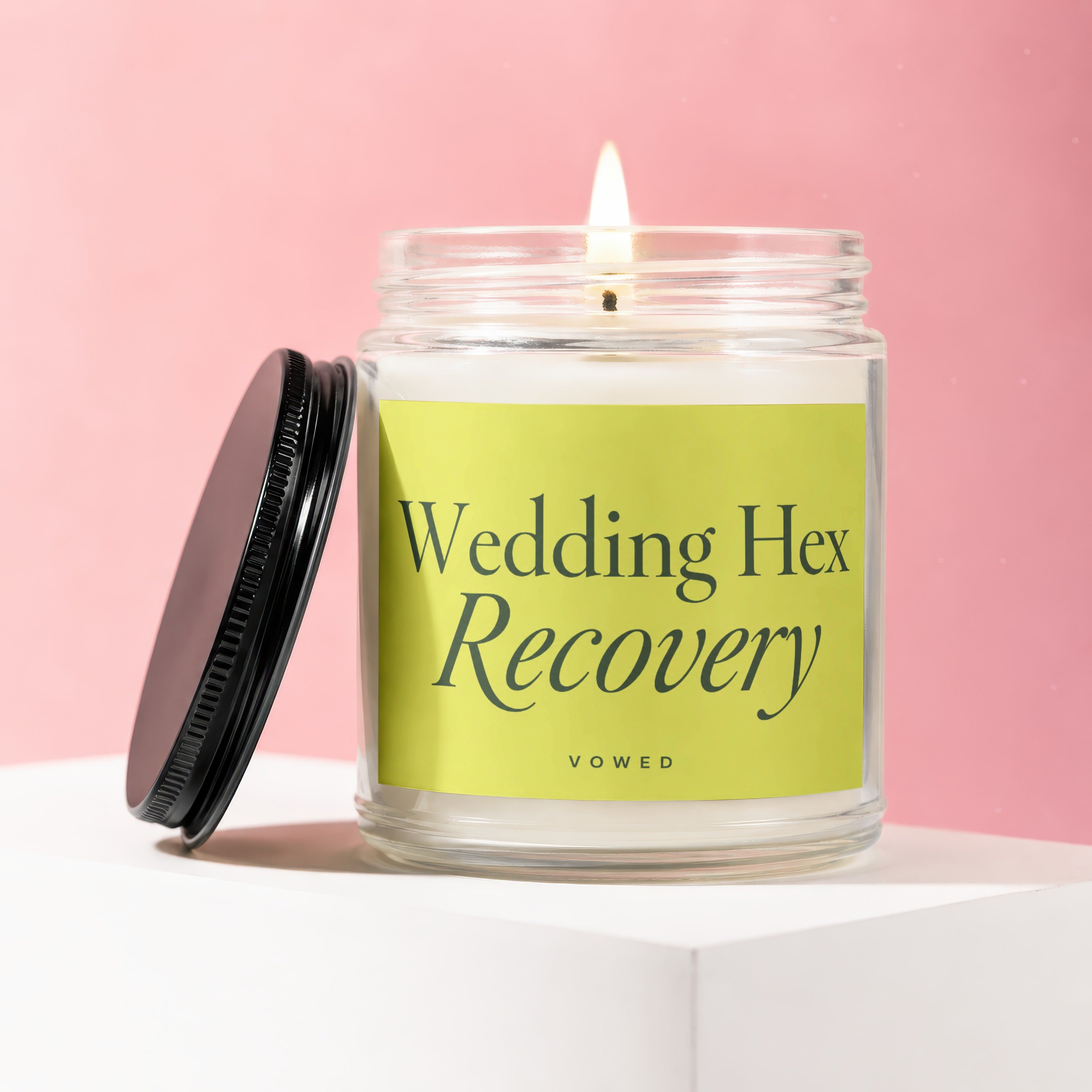 Lit candle in glass jar with black lid, label reads "Wedding Hex Recovery".