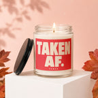 Lit candle in glass jar. Red label reads "TAKEN AF. VOWED".