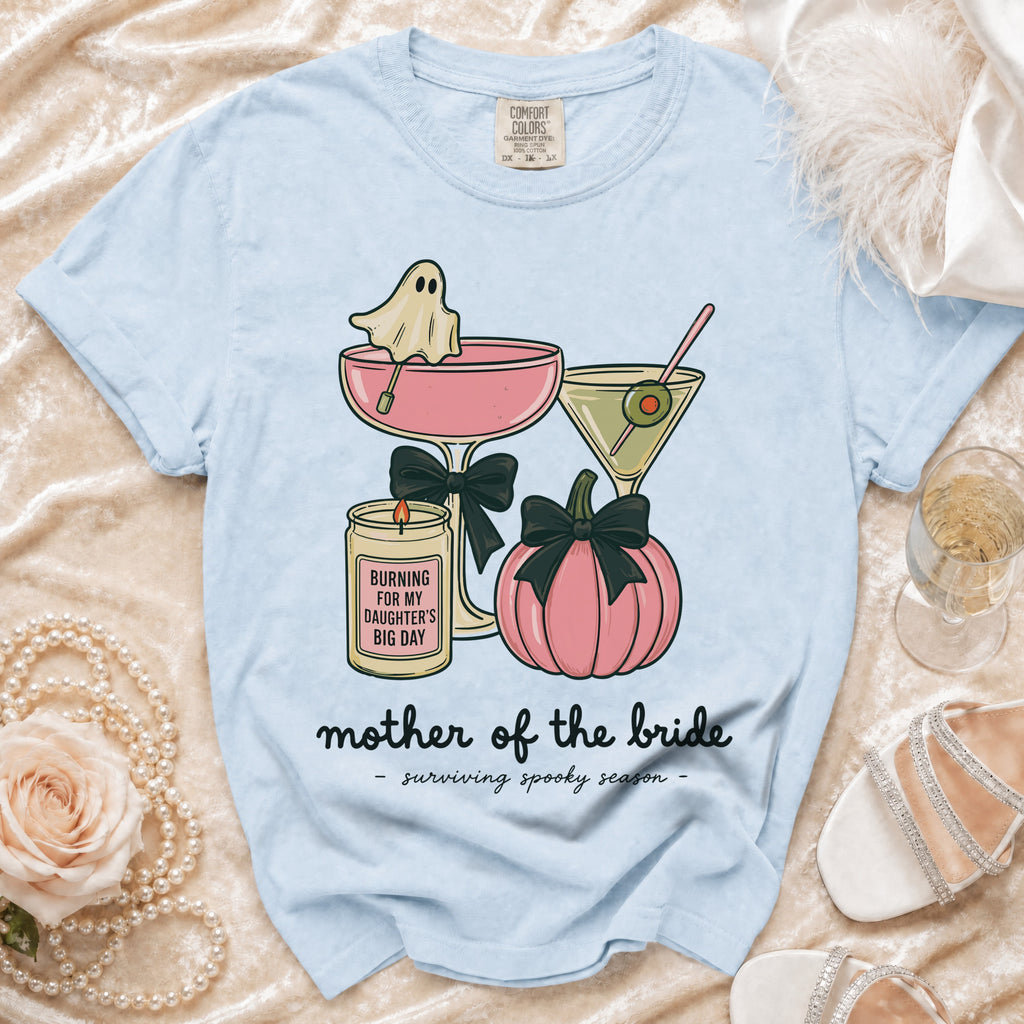 Light blue t-shirt with graphic of ghost in martini glass, pumpkin, and candle reading "Mother of the Bride".