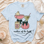 Light blue t-shirt with graphic of ghost in martini glass, pumpkin, and candle reading "Mother of the Bride".